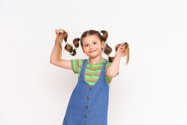 Mała dziewczynka trzyma długie włosy z zabawną fryzurą na białym tle
