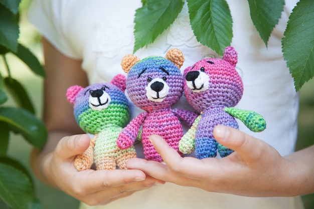 Mała dziewczynka trzyma dzianinową zabawkę w parku. Ręcznie robione, amigurumi