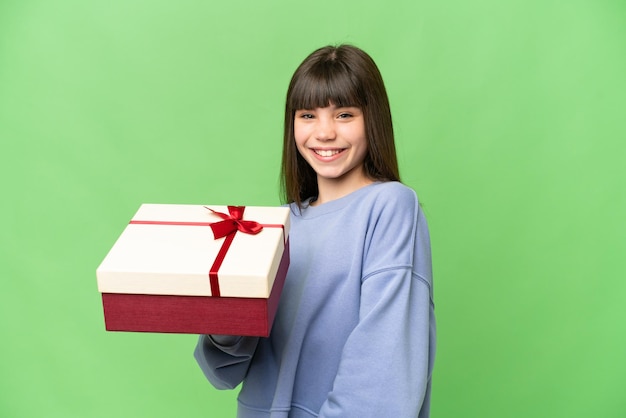 Mała dziewczynka trzyma prezent nad odizolowanym tłem klucza chrominancji, uśmiechając się dużo
