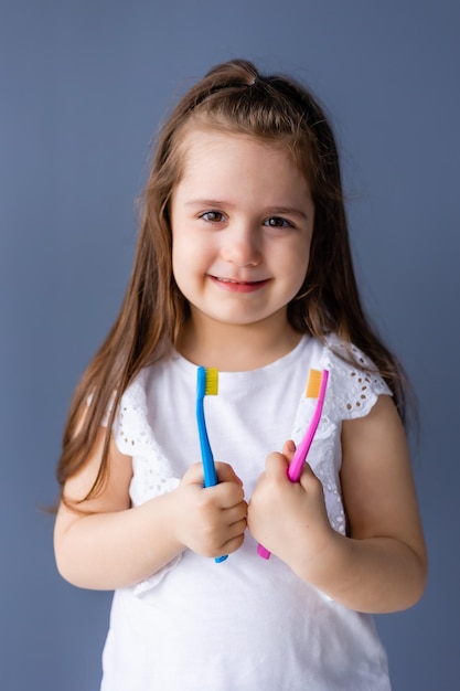 Mała dziewczynka trzyma szczoteczkę do zębów i uśmiecha się.