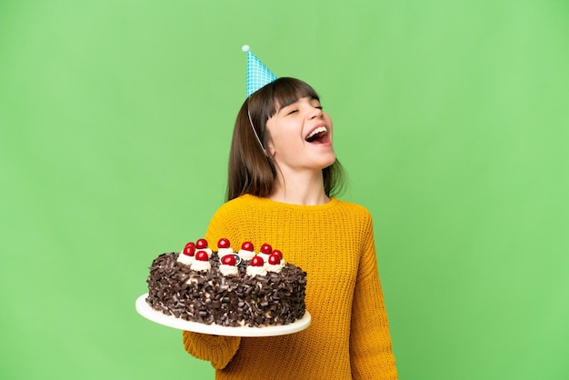 Mała dziewczynka trzyma tort urodzinowy nad izolowanym kluczem chrominancji, śmiejąc się
