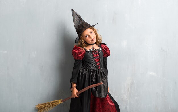 Zdjęcie mała dziewczynka ubrana jak czarownica na święta halloween i zabranie jej język