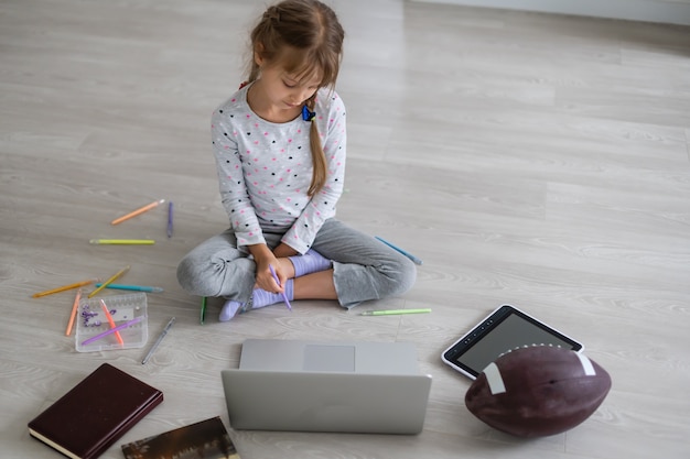 Mała dziewczynka uczy się online przy użyciu laptopa w domu