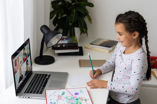 Mała dziewczynka uczy się online przy użyciu laptopa w domu