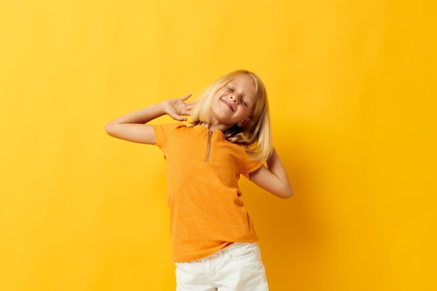 Mała dziewczynka uśmiech gesty rąk pozowanie na co dzień zabawa żółte tło niezmienione
