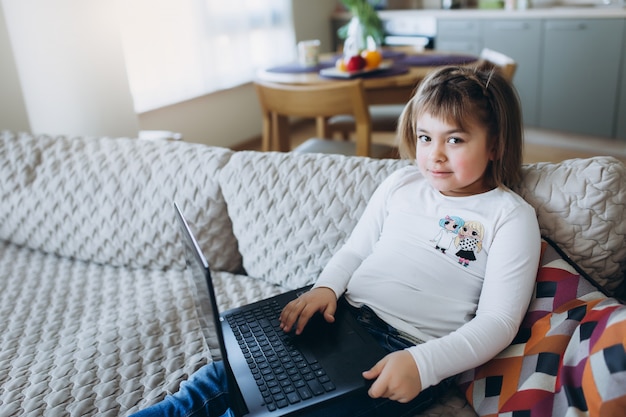 Mała dziewczynka używa laptop na kanapie
