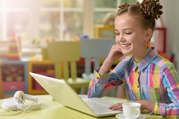 Mała dziewczynka używająca laptopa pisania i uśmiechania się