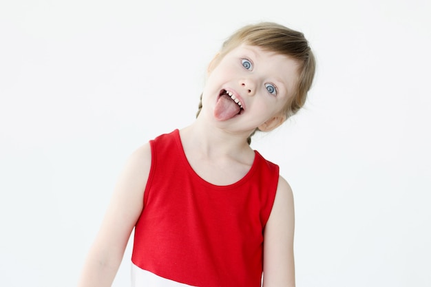 Mała dziewczynka w czerwonej sukience pokazano język