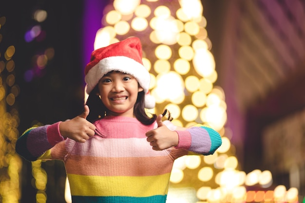 Mała dziewczynka w czerwonym kapeluszu Santa na tle bokeh. portret