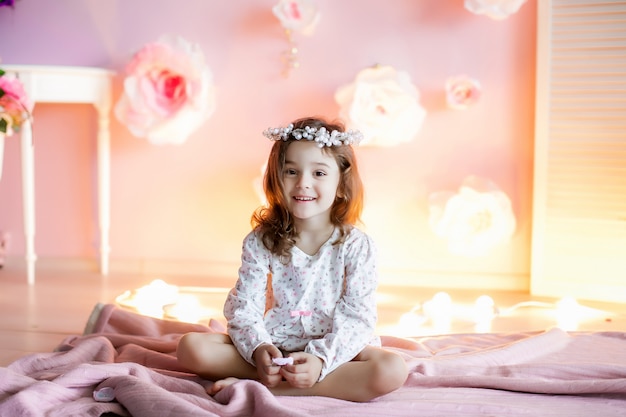 Zdjęcie mała dziewczynka w domowej atmosferze przy ścianie ze świecącymi światłami