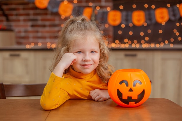 Mała dziewczynka w domu w kuchni przy stole z dynią na halloween