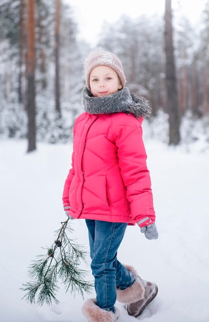 Mała Dziewczynka W Jasnej Kurtce Bawi Się W Zimowym śnieżnym Lesie.