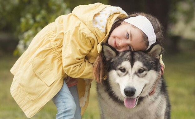 Mała dziewczynka w kolorowych ubraniach ze swoim zwierzakiem zabawnym przyjacielem malamute alaskan dog