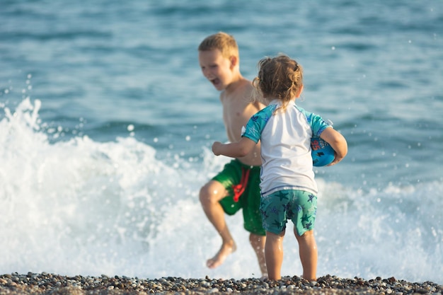 Mała dziewczynka w kostiumie kąpielowym bawi się z bratem w piasku na morskiej plaży