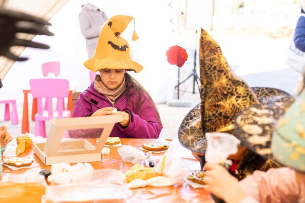 Zdjęcie mała dziewczynka w kostiumie na halloween bawi się piernikowymi ciasteczkami jak dynia.