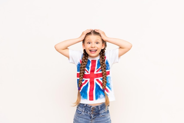 Mała dziewczynka w koszulce z brytyjską flagą trzymała się za głowę Kursy angielskiego dla dzieci w wieku szkolnym