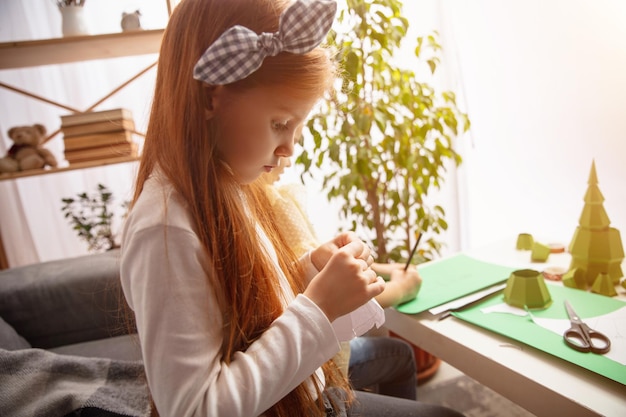 Zdjęcie mała dziewczynka w kreatywności domu. happy kid robi ręcznie robione zabawki do gier lub nowego roku