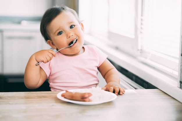 Mała dziewczynka w kuchni, jedzenie kiełbasy i puree ziemniaczanym