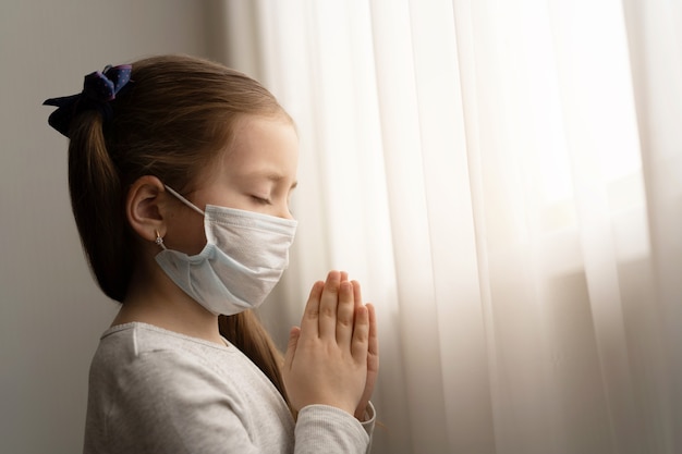 Mała Dziewczynka W Masce Do Ochrony Covid-19. Modliła Się Rano O Nowy Dzień Wolności Dla światowego Wirusa Koronowego. Mała Dziewczynka Ręka Modląc Się O Dziękuję Bogu