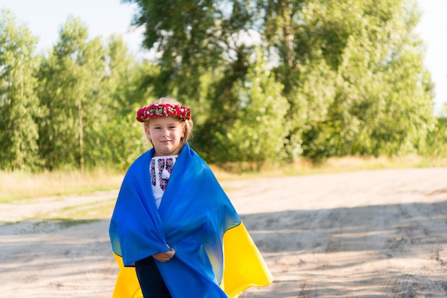 mała dziewczynka w narodowym stroju ukraińskim - vyshyvanka. Ukraina, pole. ręce flagi Ukrainy