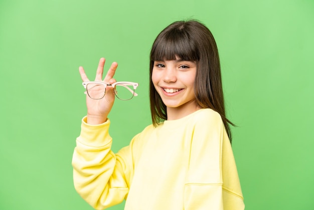 Mała dziewczynka w okularach na izolowanym tle klucza chrominancji, bardzo się uśmiecha