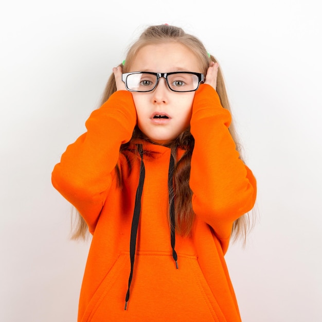 Mała dziewczynka w pomarańczowym kostiumu i okularach Emocje portret na białym tle