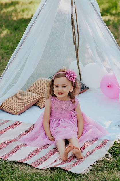 mała dziewczynka w różowej sukience bawi się w ogrodzie