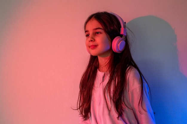 Mała dziewczynka w słuchawkach stoi w neonowym świetle