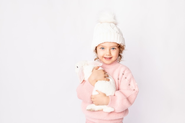 Mała dziewczynka w zimowe ubrania trzyma królika na białym tle. Koncepcja nowego roku, miejsce na tekst