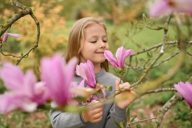 Mała dziewczynka wącha różową magnolię