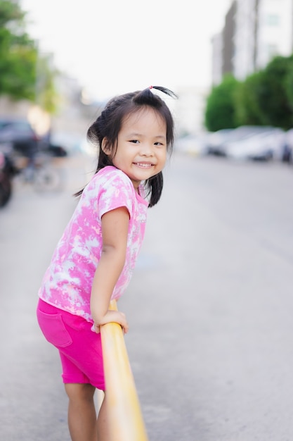 Mała dziewczynka wspina się koloru żółtego ogrodzenie w parku