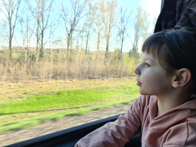 Mała dziewczynka wygląda przez okno i jedzie pociągiem