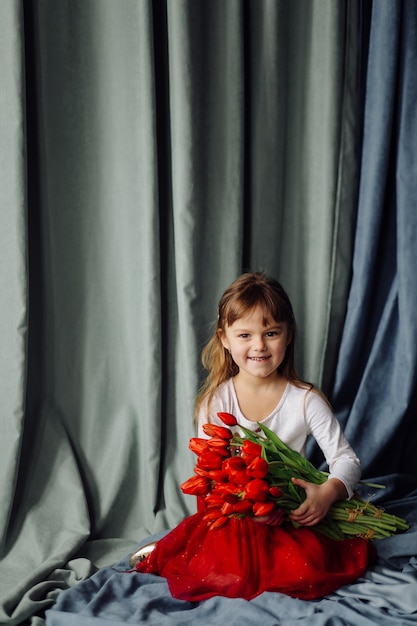 Mała dziewczynka z bukietem czerwonych tulipanów