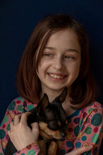 Mała dziewczynka z chihuahua. Dziewczyna trzyma chihuahua. Dziewczyna ze swoim zwierzakiem w ramionach.