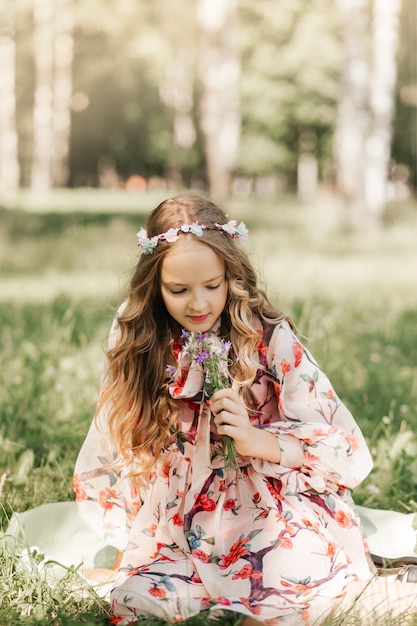 Mała dziewczynka z długimi siwymi włosami i bukietem polnych kwiatów w parku
