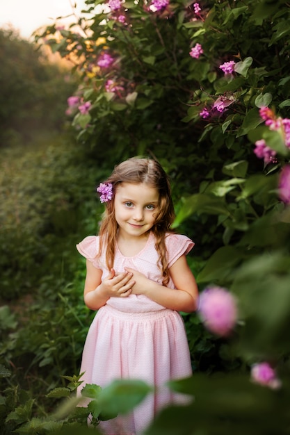 Mała dziewczynka z kwiatami bez w ogródzie.