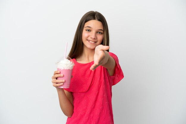 Mała dziewczynka z truskawkowym koktajlem mlecznym na białym tle, ściskając ręce, aby zamknąć dobrą ofertę