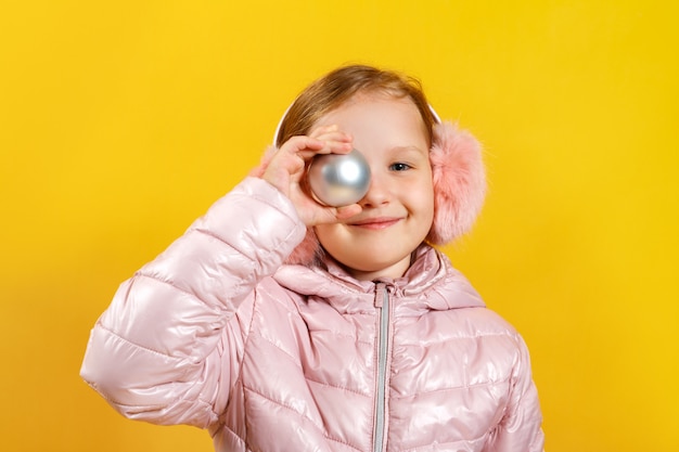 Zdjęcie mała dziewczynka z zabawkarską bożenarodzeniową piłką.