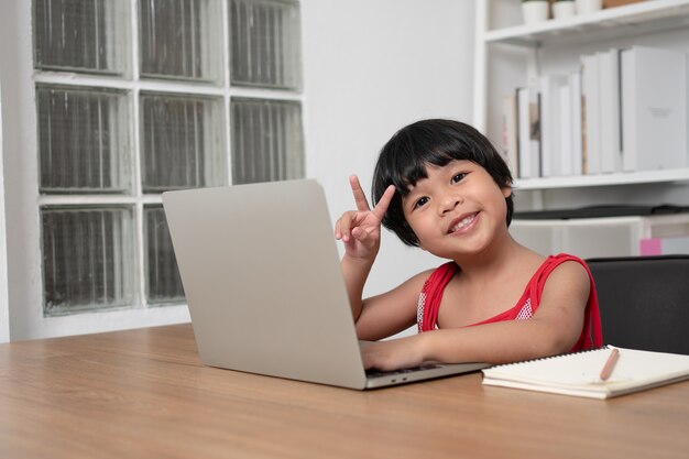 Mała dziewczynka za pomocą laptopa przy stole