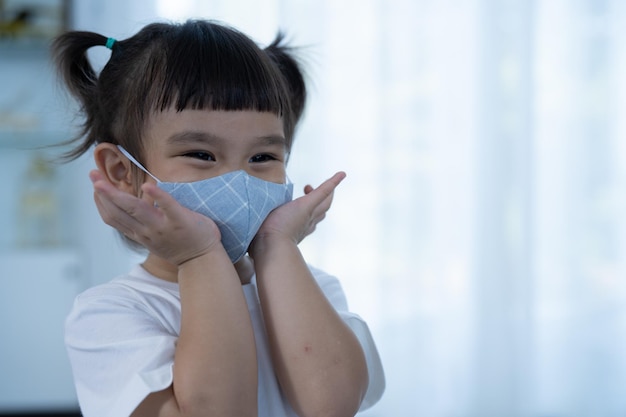 Mała dziewczynka zakłada maskę ochronną na twarz Maska medyczna zapobiegająca pandemii koronawirusa