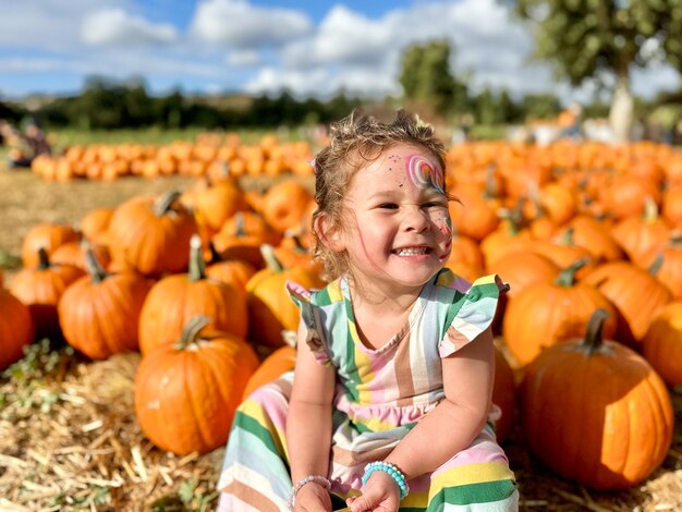 Mała dziewczynka zbierająca dyni na Halloween, dziecko bawiące się na polu squasha.