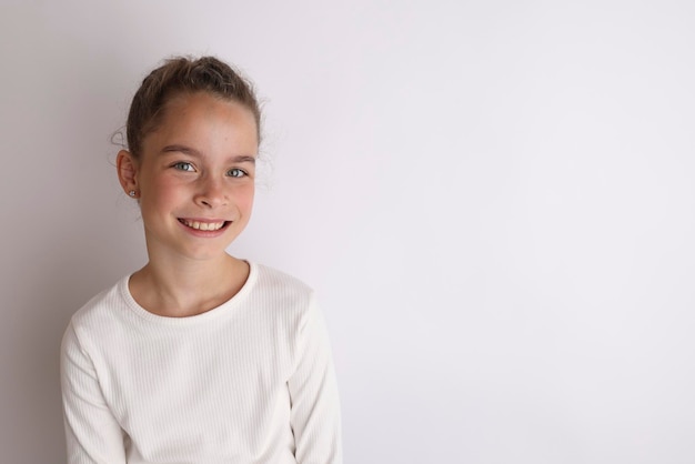 Mała emocjonalna nastolatka w białej koszuli 11 12 lat na izolowanym białym tle Portret studyjny dla dzieci Umieść tekst do skopiowania miejsca na napis reklamujący towary dla dzieci