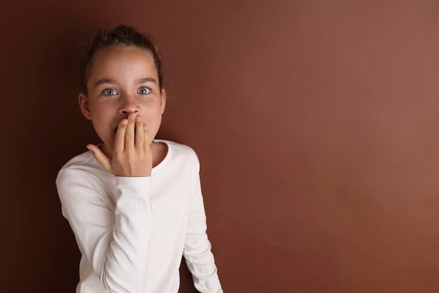 Mała emocjonalna nastolatka w bieli 11 12 lat na odosobnionym brązowym tle czekolady Portret studyjny dla dzieci Umieść tekst do skopiowania miejsca na napis reklamujący towary dla dzieci
