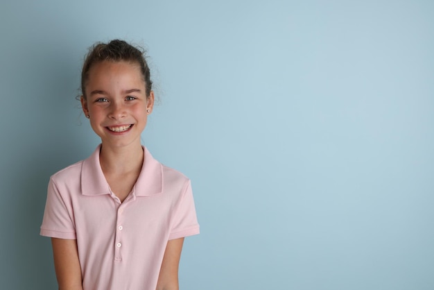 Mała emocjonalna nastolatka w różowej koszuli 11 12 lat na odizolowanym niebieskim tle Portret studyjny dla dzieci Umieść tekst do skopiowania miejsca na podpis reklamujący towary dla dzieci