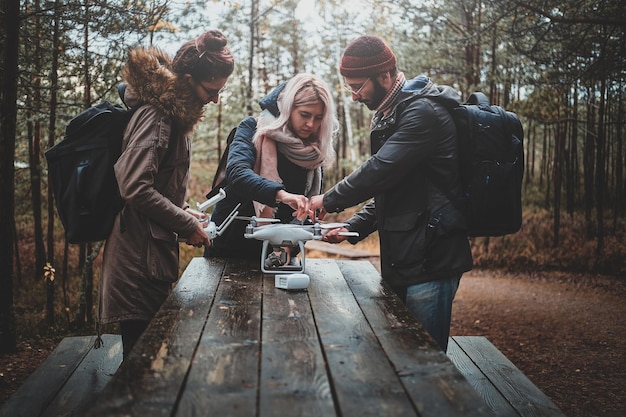 Zdjęcie mała grupa przyjaciół montuje drona w leśnym parku przy pomocy drewnianego stołu.
