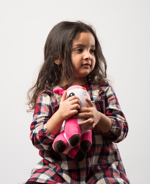 Mała indyjska azjatycka dziewczyna bawi się wypchaną miękką zabawką