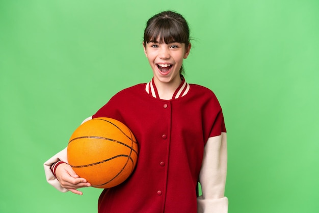 Mała kaukaska dziewczyna gra w koszykówkę na odosobnionym tle z wyrazem twarzy zaskoczenia