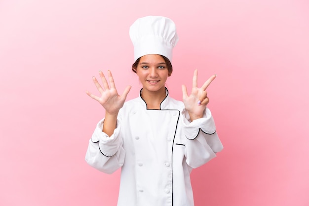 Mała kaukaska dziewczyna kucharza odizolowana na różowym tle, licząc osiem palcami