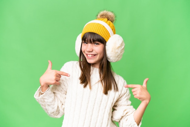 Mała kaukaska dziewczyna ubrana w zimowe mufki na odizolowanym tle, dumna i zadowolona z siebie