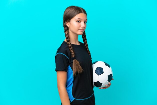 Mała kaukaska dziewczynka na białym tle na niebieskim tle z piłką nożną